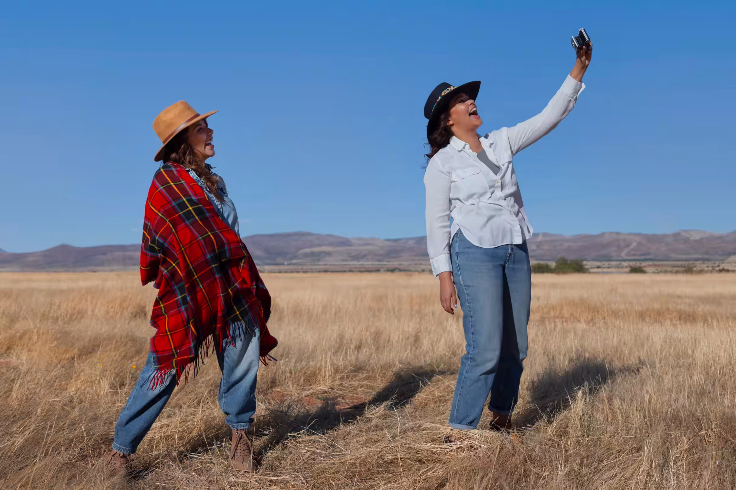 Couple watching the sunset over the plains with drinks in hand — 2400×1400